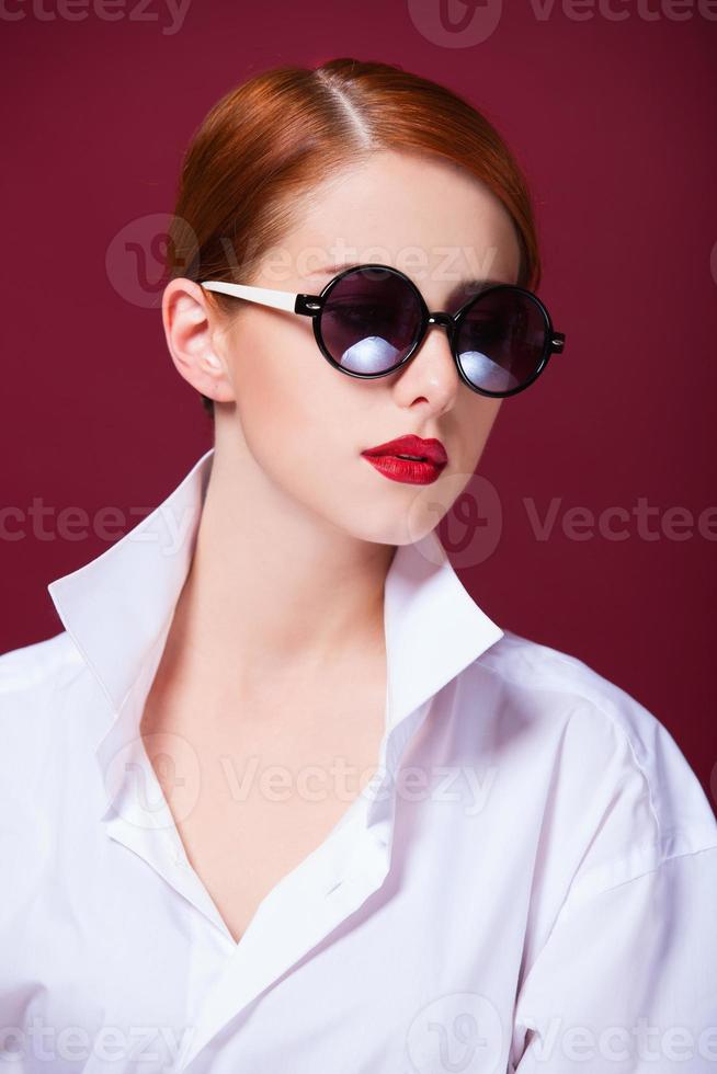 rossa in occhiali da sole su sfondo rosso foto