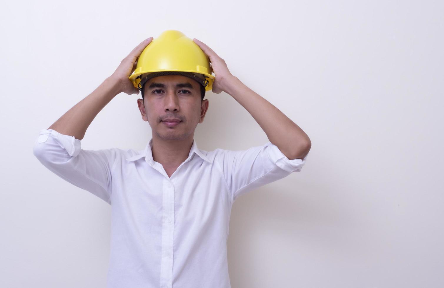 ingegnere con le mani incrociate che indossa il casco giallo su sfondo bianco foto