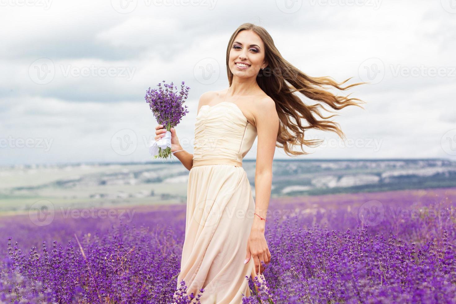 bella ragazza sorridente indossa abito al campo di lavanda viola foto