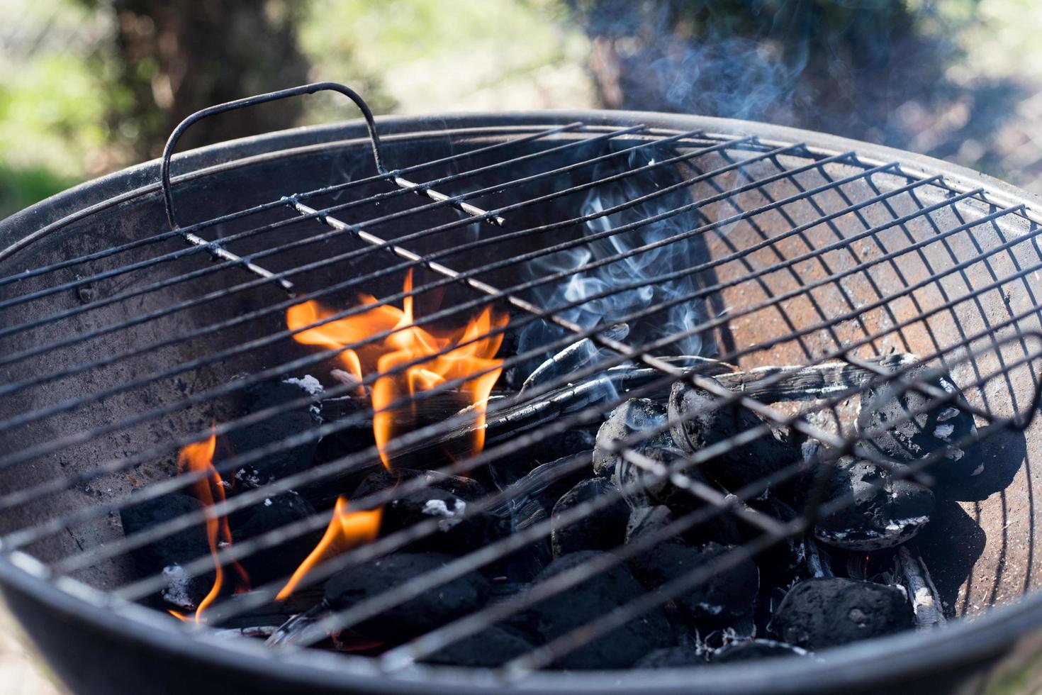 accendere la griglia, fiamme visibili e pezzi di carbone, concetto di barbecue foto