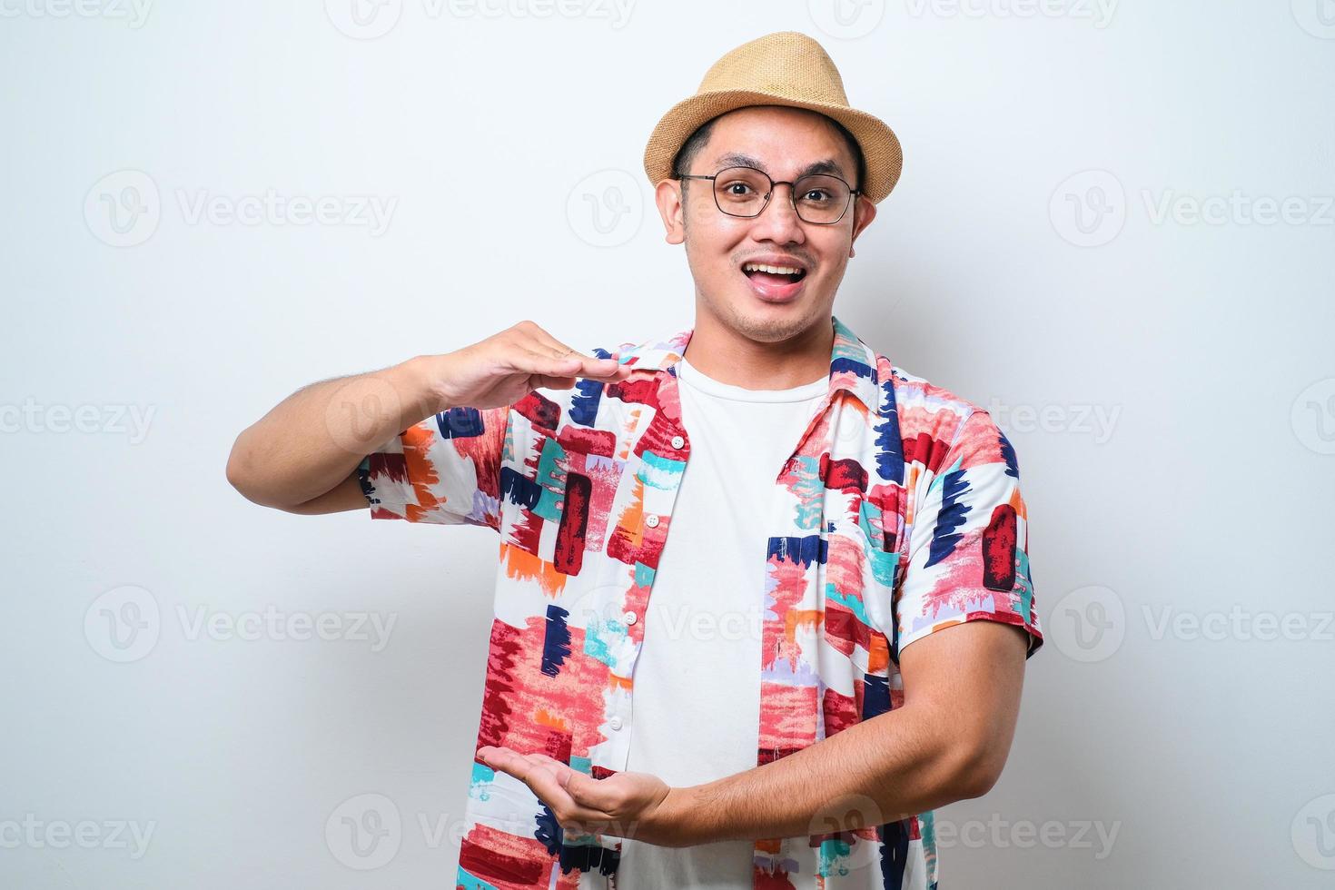 uomo asiatico che fa gesti con le mani che mostrano un segno di grandi e grandi dimensioni, simbolo di misura. sorridente guardando la telecamera. concetto di misurazione. foto