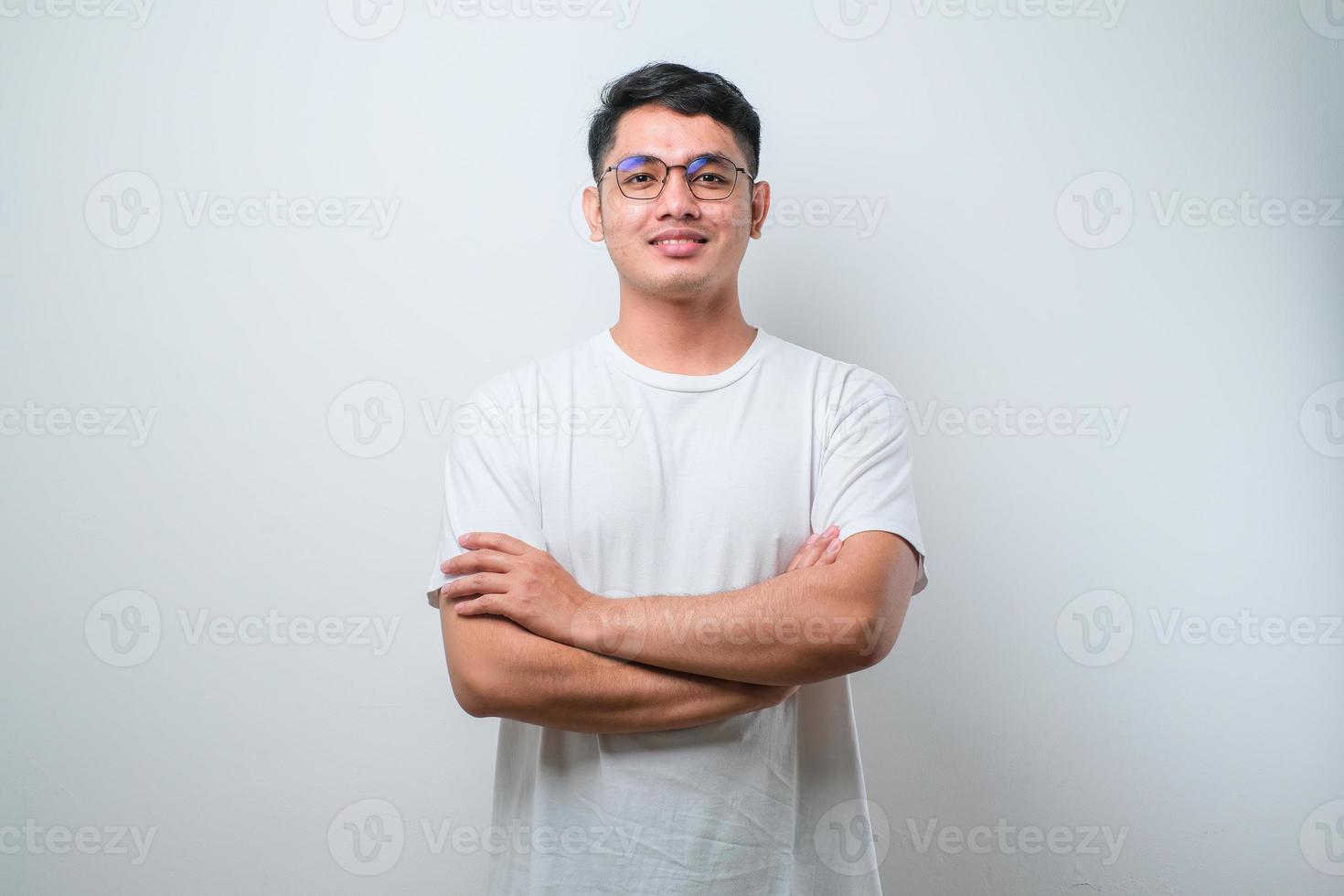 potrait di giovane uomo asiatico bello che indossa camicia casual e occhiali, faccia felice sorridente con le braccia incrociate guardando la telecamera foto