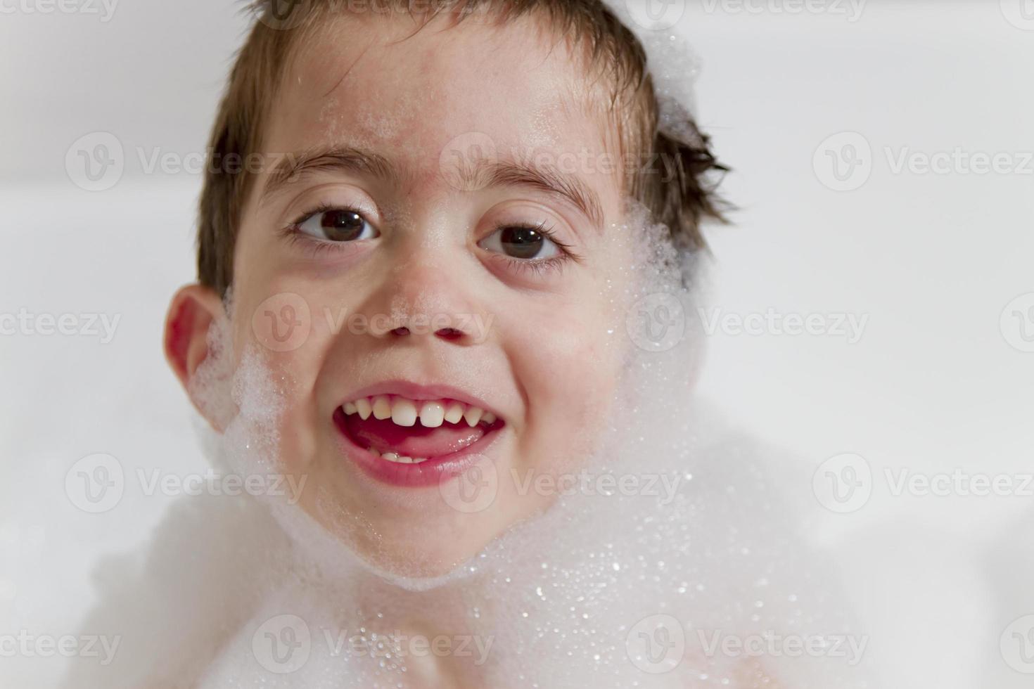 Ritratto di bambino sorridente mentre il bagno di bolle. foto