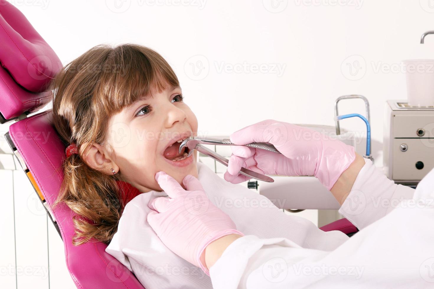 il dentista ha estratto il dente bambina con una pinza foto