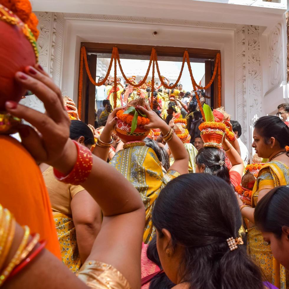 nuova delhi, india 03 aprile 2022 - donne con kalash sulla testa durante il tempio di jagannath mangal kalash yatra, devoti indù indiani portano pentole di terracotta contenenti acqua sacra con una noce di cocco in cima foto