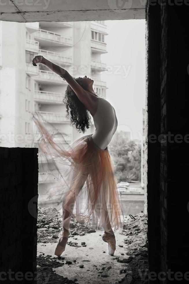 un'affascinante ballerina in body posa elementi di balletto in un copricapo in uno studio fotografico foto