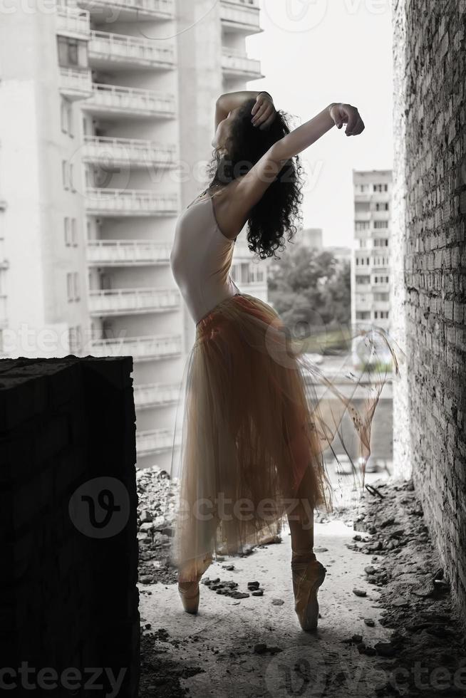 un'affascinante ballerina in body posa elementi di balletto in un copricapo in uno studio fotografico foto