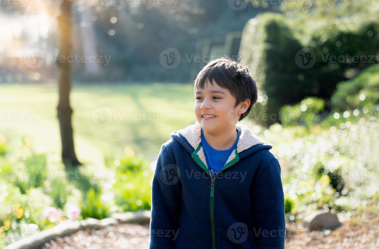 felice ragazzo che gioca all'aperto in giardino, ritratto bambino con la faccia sorridente si diverte a giocare fuori la mattina, bambino che si rilassa in una giornata di sole primaverile o estiva nel parco. foto