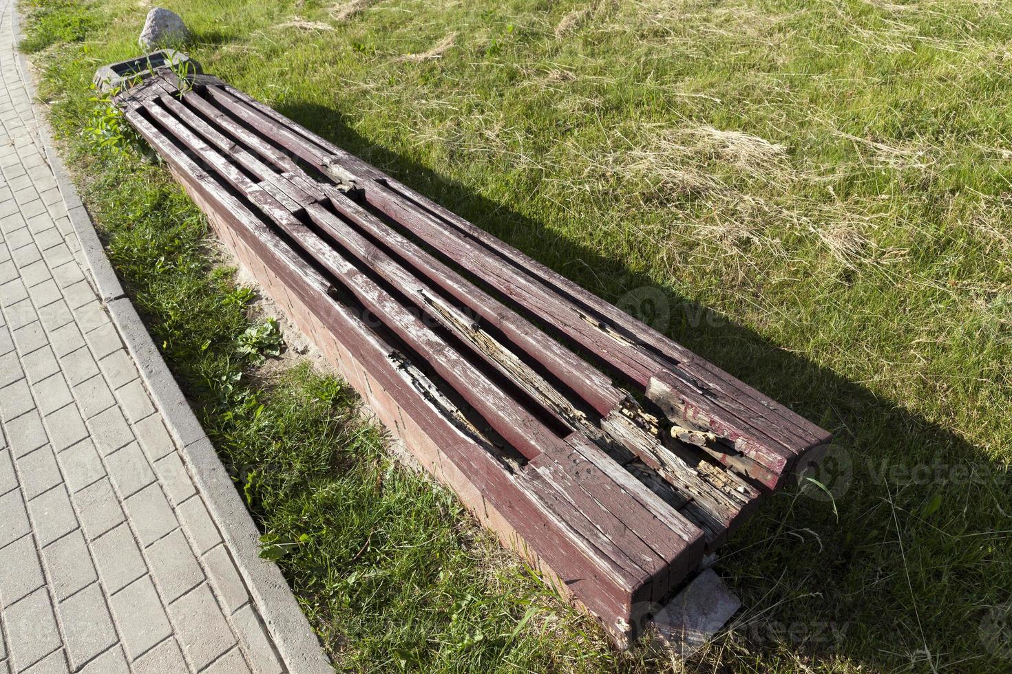 una vecchia panca di legno in decomposizione nel parco foto