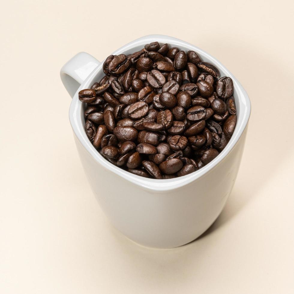 chicchi di caffè in tazza bianca su sfondo colorato foto