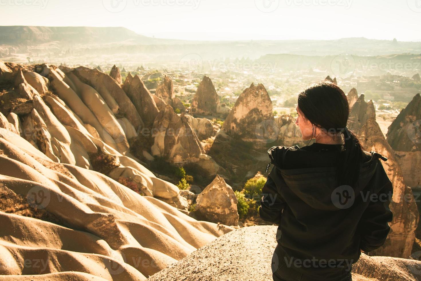 la persona di sesso femminile premurosa osserva la valle drammatica sull'alba nebbiosa del mattino con lo sfondo dei camini delle fate. esplorazione in solitaria in Turchia. destinazione di viaggio cinematografica-cappadocia foto