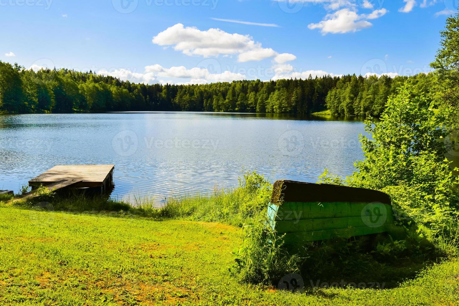 barche capovolte dalla calma riva blu del lago nella campagna della lituania. pesca nei paesi baltici all'aperto in estate foto