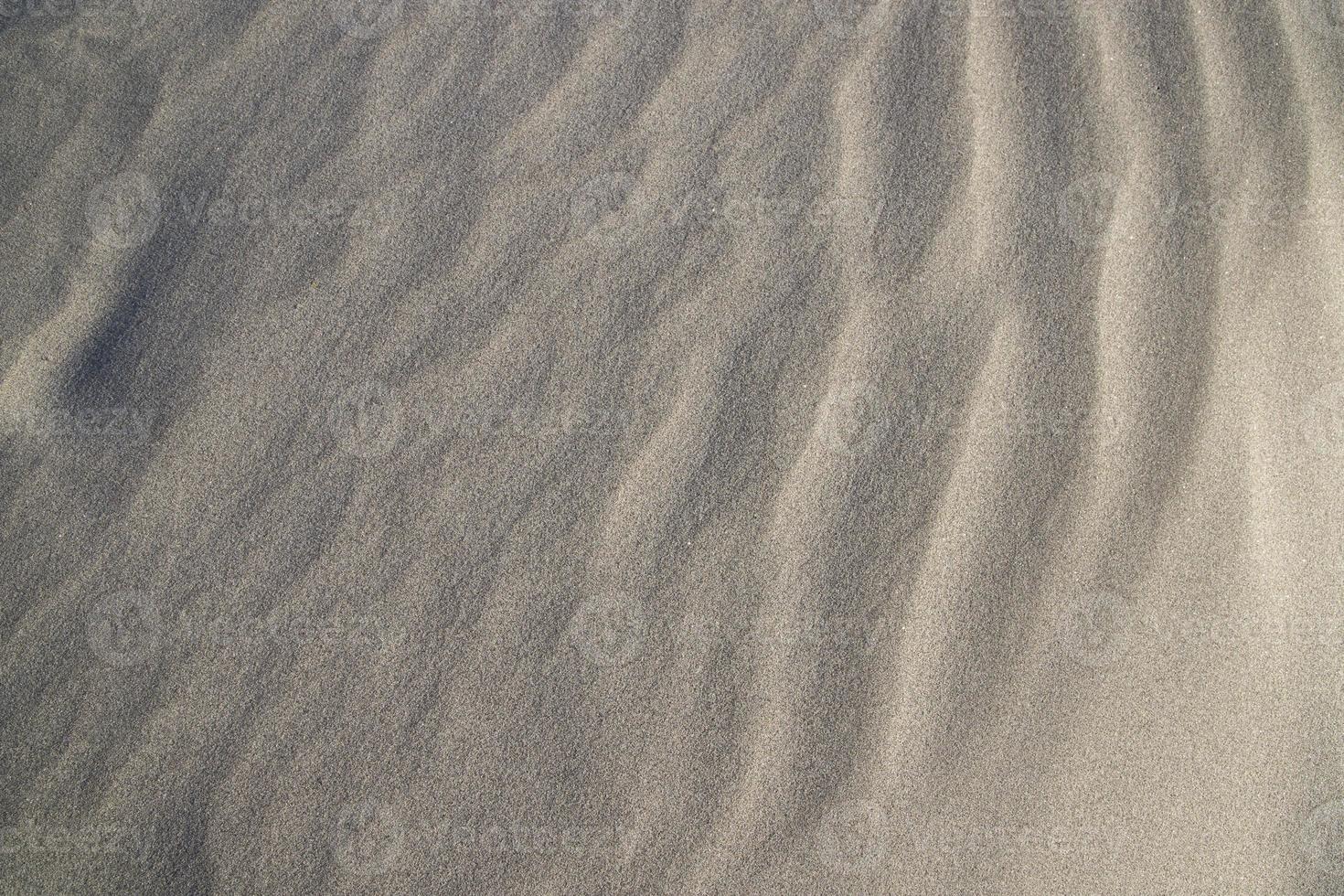 consistenza della sabbia. sfondo strutturato di sabbia ondulata. spiaggia di sabbia strutturata foto