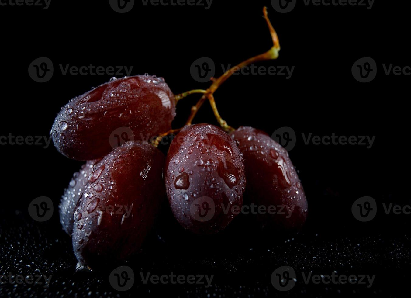 diversi acini d'uva succosi sono isolati su uno sfondo nero. foto