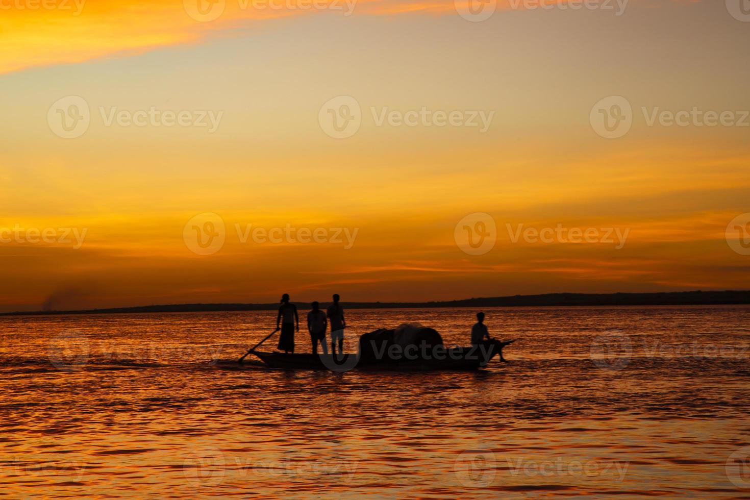 una barca da pesca sul mare contro il cielo arancione durante il tramonto foto