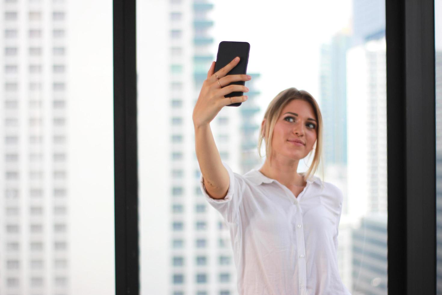 ritratto di una giovane donna attraente che fa foto selfie su smartphone in un moderno edificio per uffici sullo sfondo