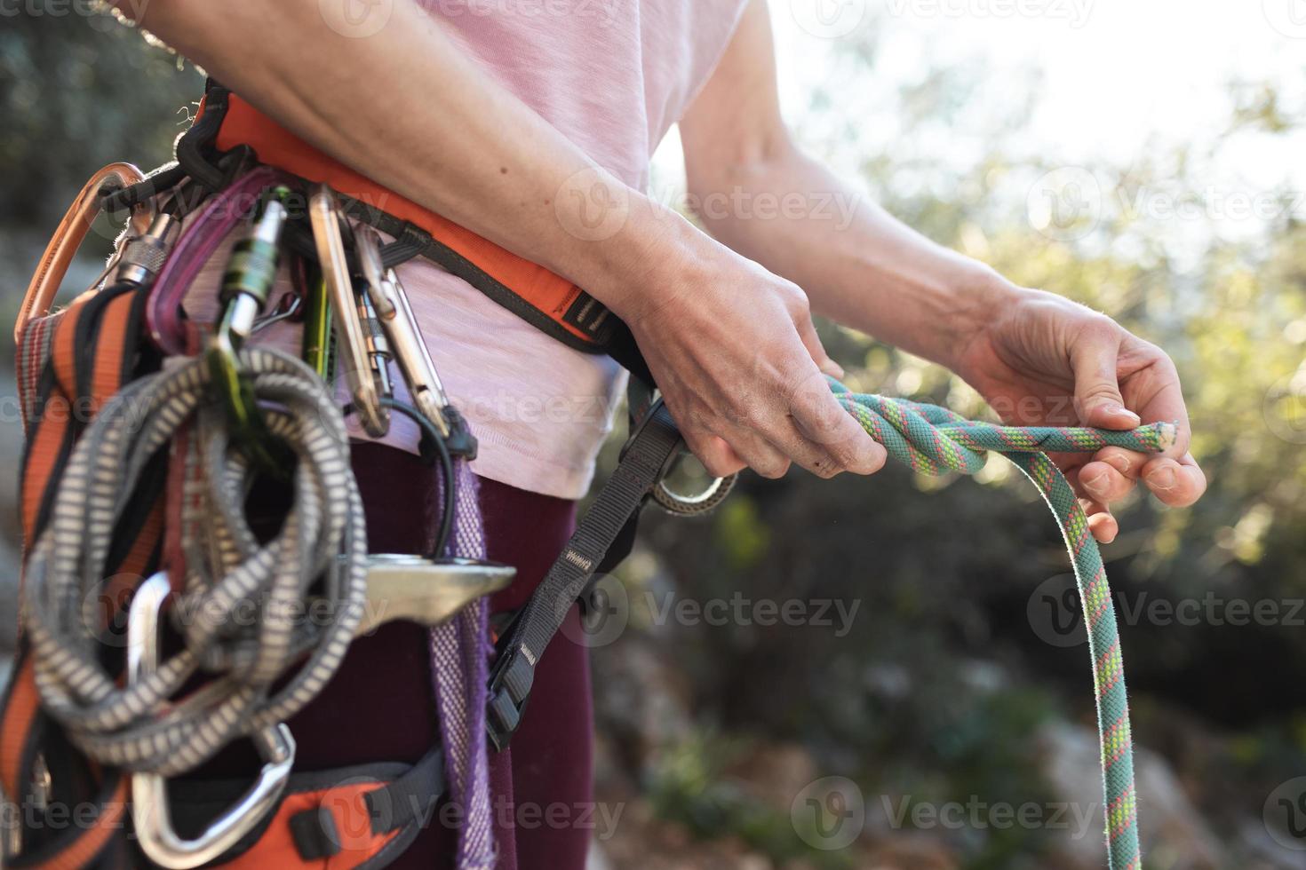 uno scalatore prepara l'attrezzatura per l'arrampicata, la donna tiene una corda, un nodo foto