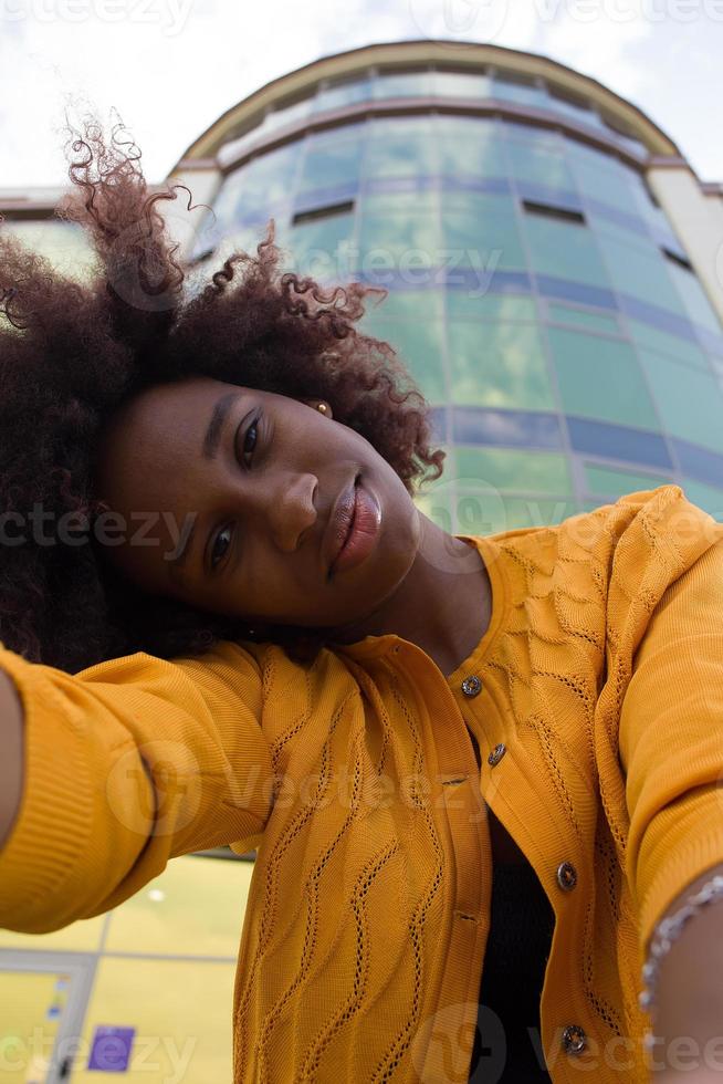 una donna afroamericana felice e giovane prende un selfie, primo piano foto