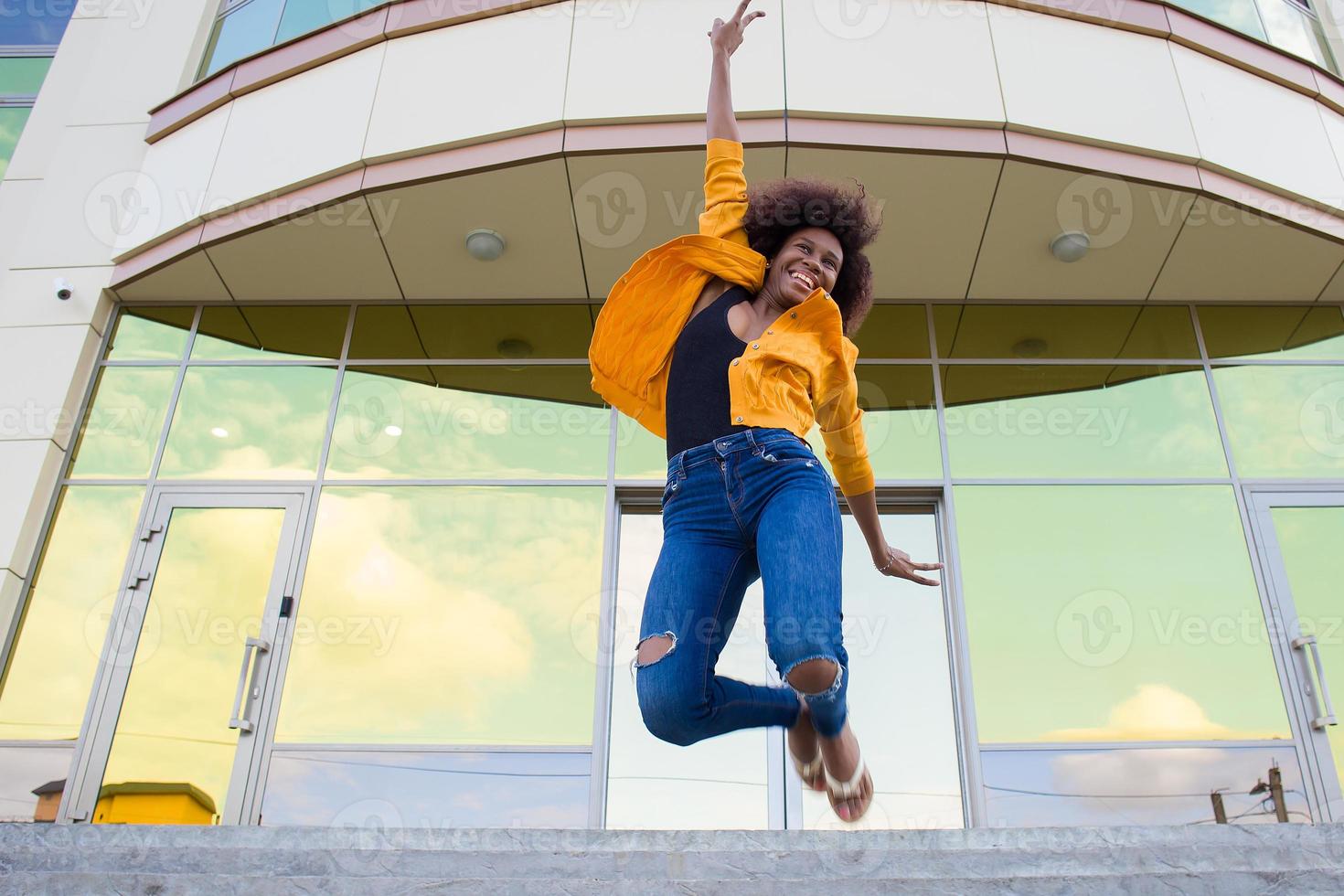 la felice e giovane donna afroamericana per strada che si diverte foto