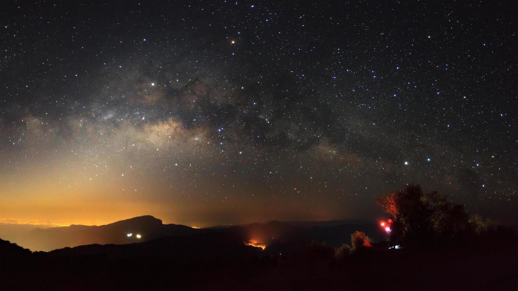 panorama della galassia della via lattea con la città leggera a doi inthanon chiang mai, tailandia.fotografia a lunga esposizione.con grano foto