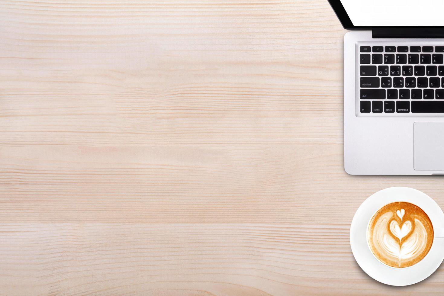 vista dall'alto tazza di caffè latte art e computer portatile notebook sul tavolo di legno foto