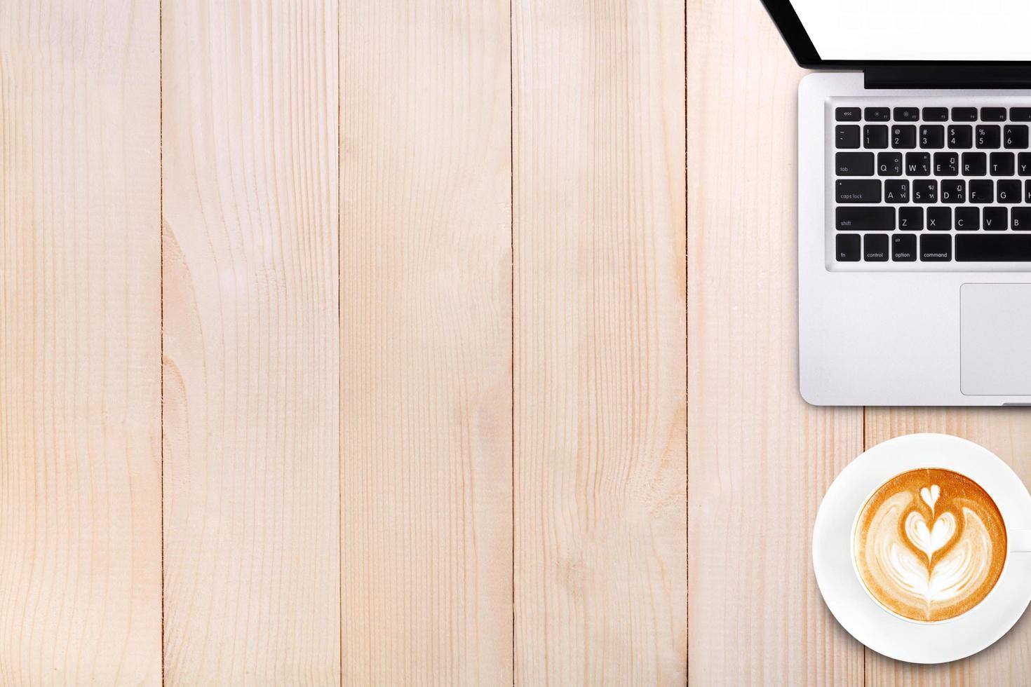 vista dall'alto tazza di caffè latte art e computer portatile notebook sul tavolo di legno foto