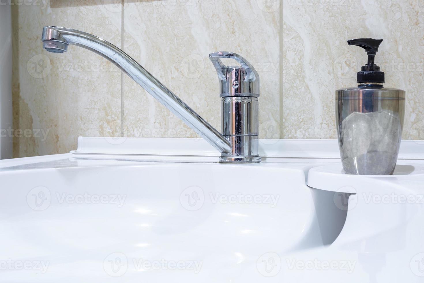 lavandino del rubinetto dell'acqua con rubinetto nel bagno soppalcato costoso. dettaglio di una cabina doccia ad angolo con attacco doccia a parete foto