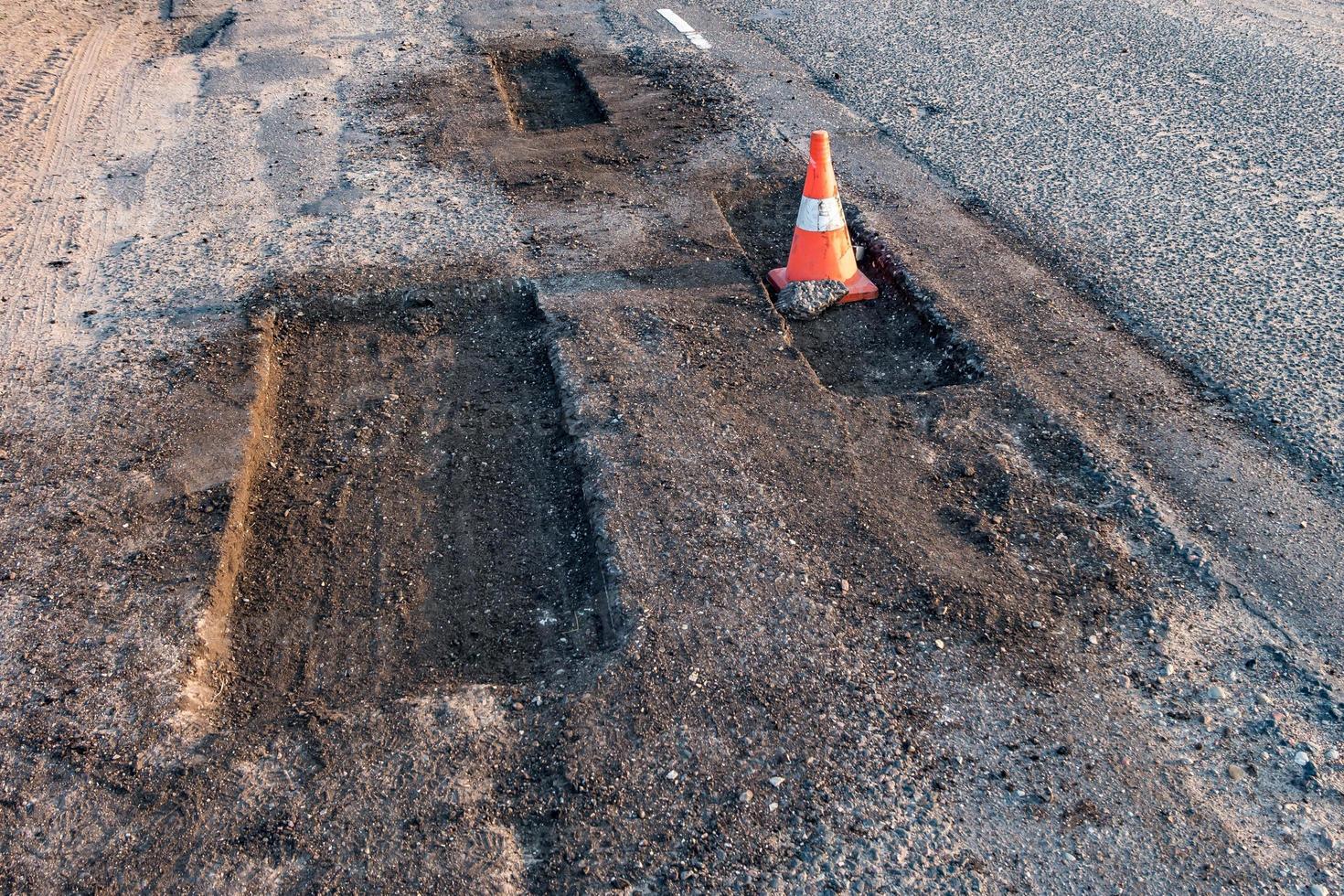 cono di pericolo di traffico arancione bianco sulla riparazione della strada asfaltata foto