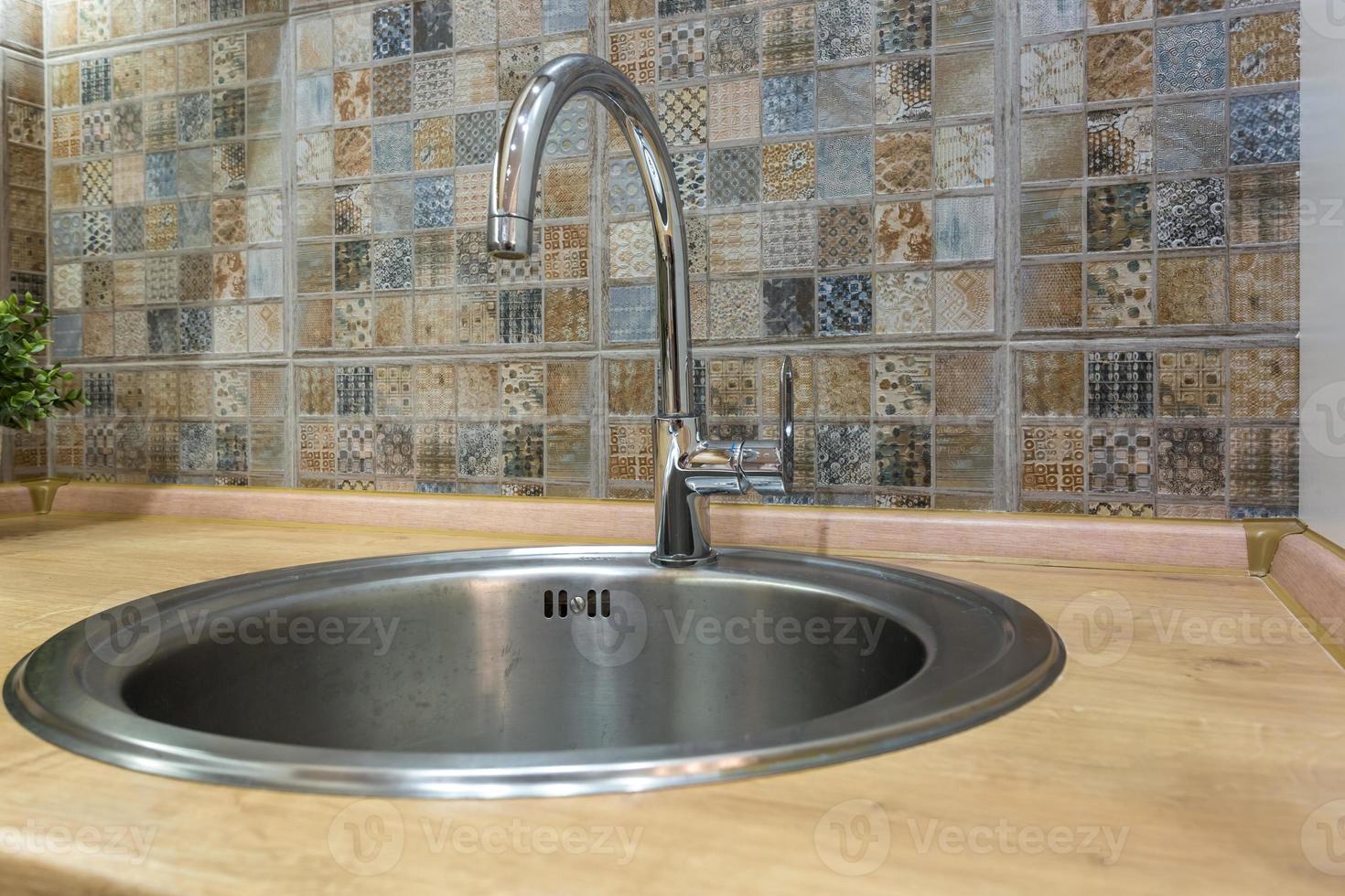 Lavello del rubinetto dell'acqua in acciaio con rubinetto in una cucina a soppalco costosa foto