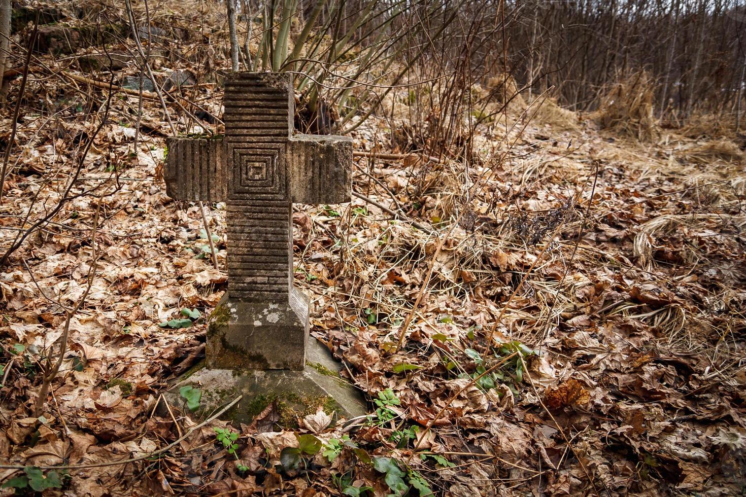 vecchia croce tombale della prima guerra mondiale ricoperta di muschio e vecchie foglie nella foresta autunnale foto