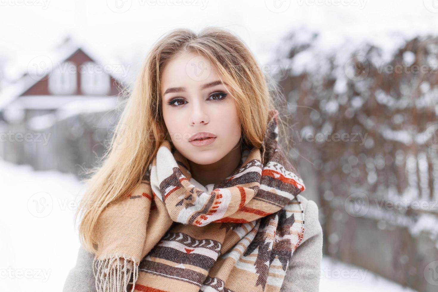 ritratto ravvicinato di una giovane bella ragazza con sciarpa vintage invernale sullo sfondo del villaggio foto