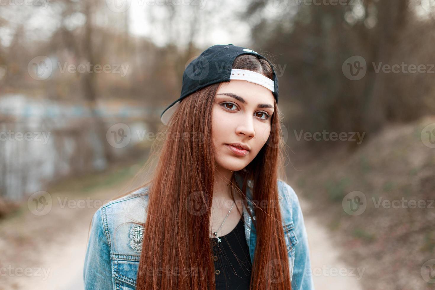 ritratto ravvicinato di una bella giovane donna con un berretto da baseball nero e una giacca di jeans. foto