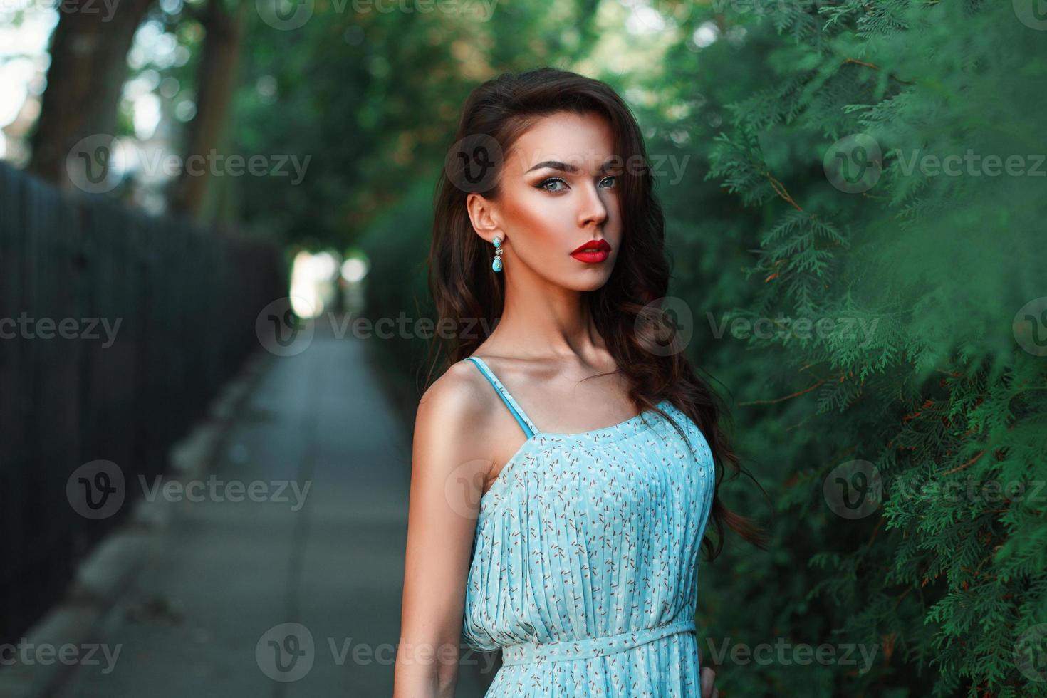 bella donna di moda che cammina nel parco in un vestito turchese. foto