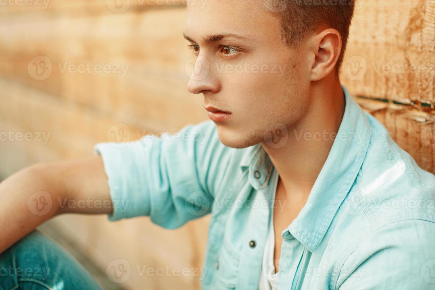 giovane uomo triste in abiti denim sullo sfondo della parete di legno foto