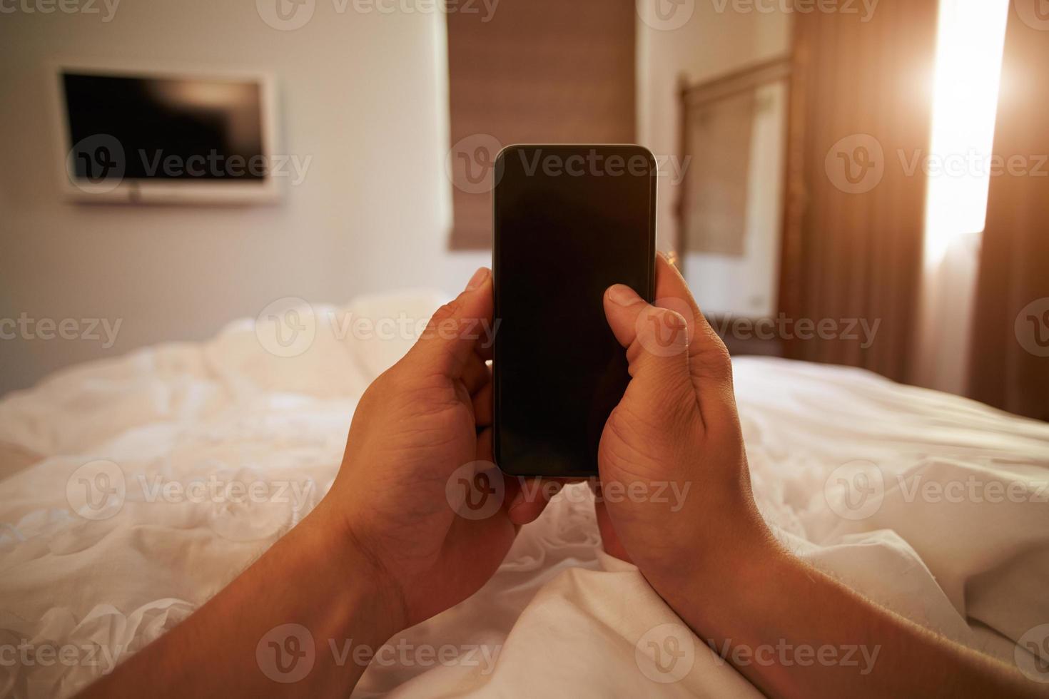 pov di persona a letto guardando il telefono cellulare foto