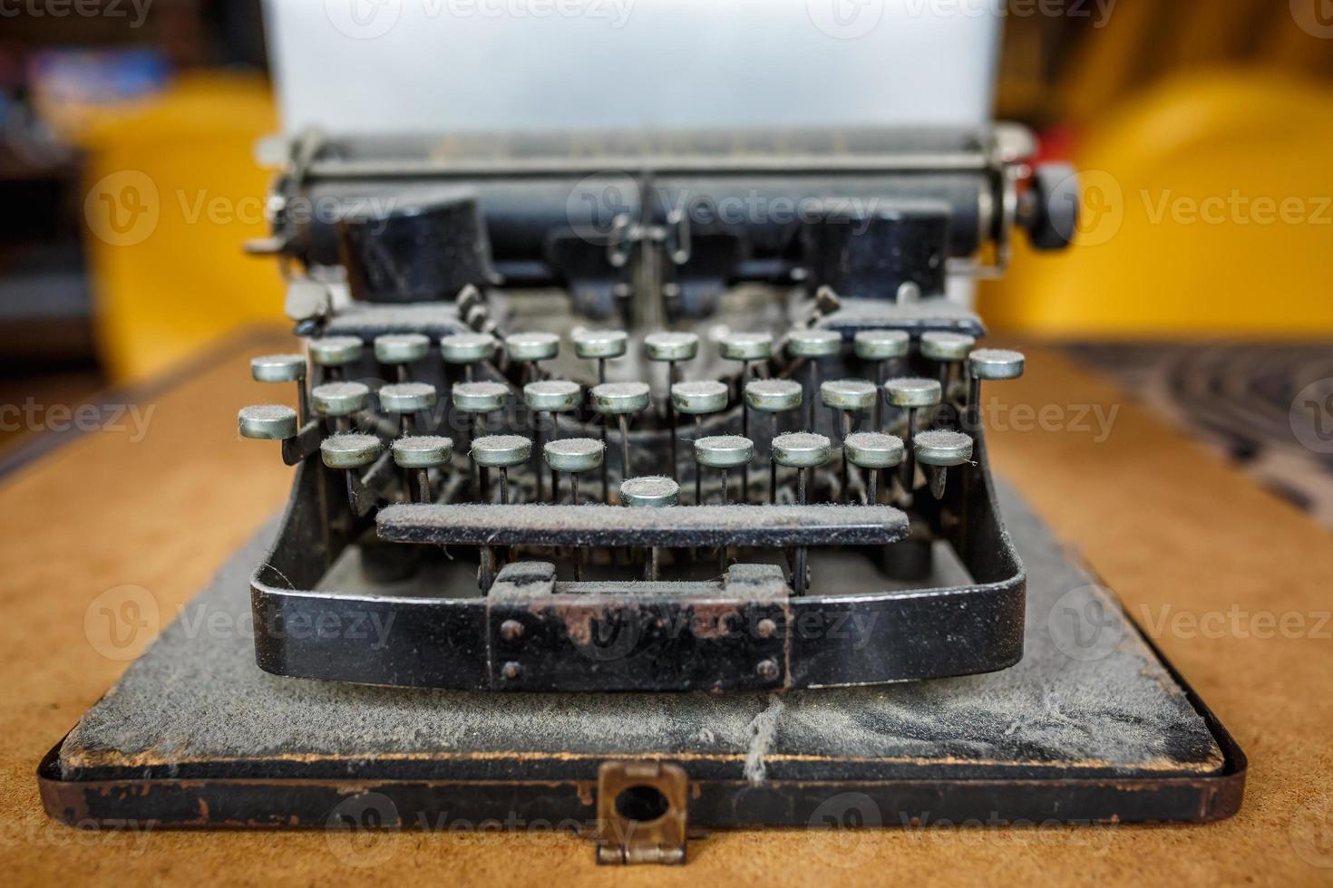 vecchia macchina da scrivere vintage ricoperta di polvere con foglio di carta bianca foto