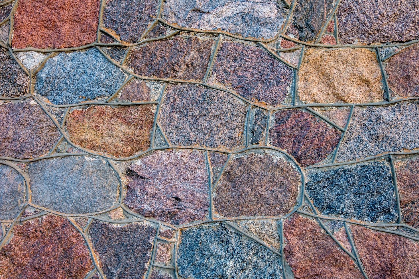 superficie grigia della parete di vecchie pietre con intonaco nelle fessure foto