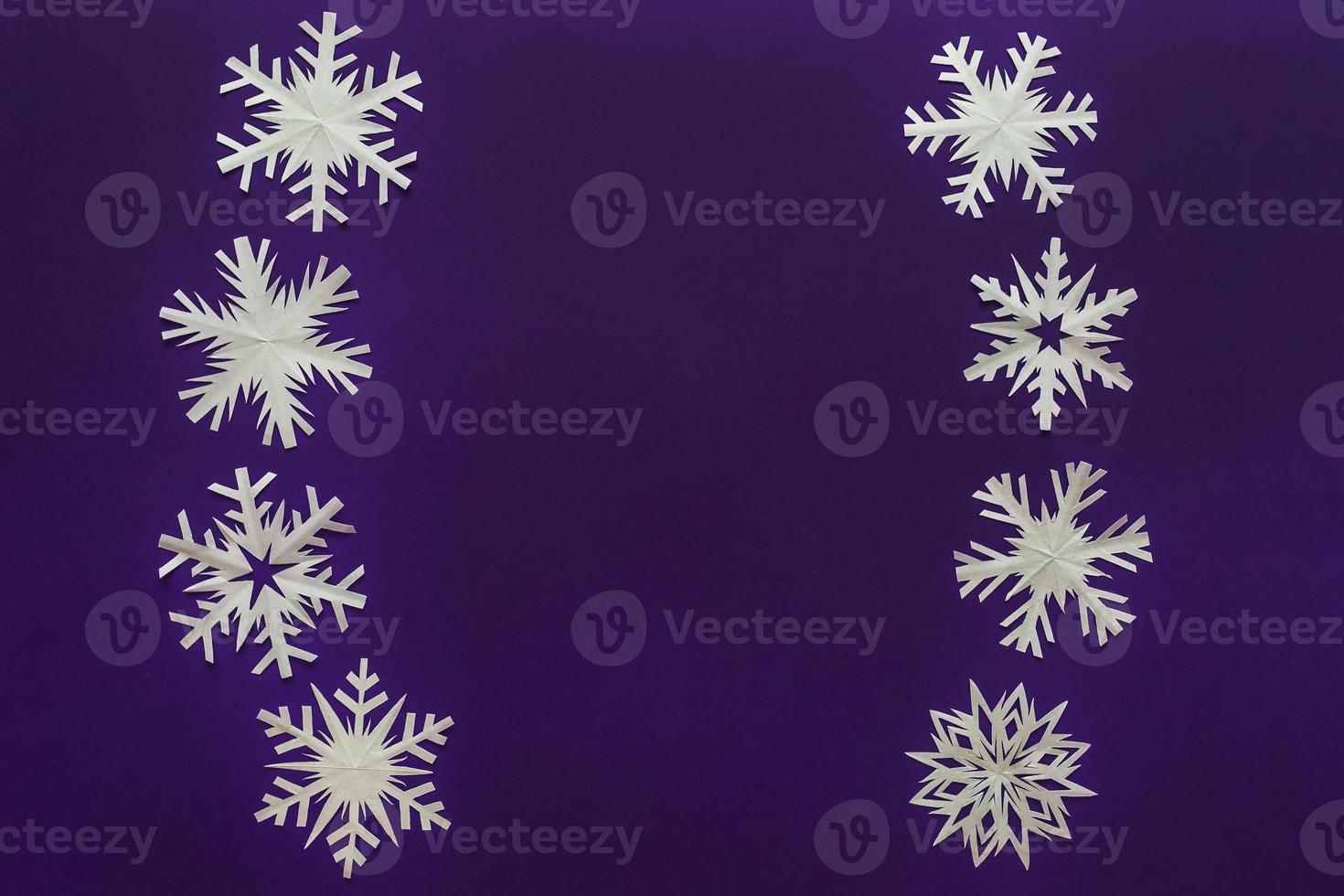 fiocchi di neve di carta bianca diverse forme e dimensioni su sfondo viola. vista dall'alto. foto