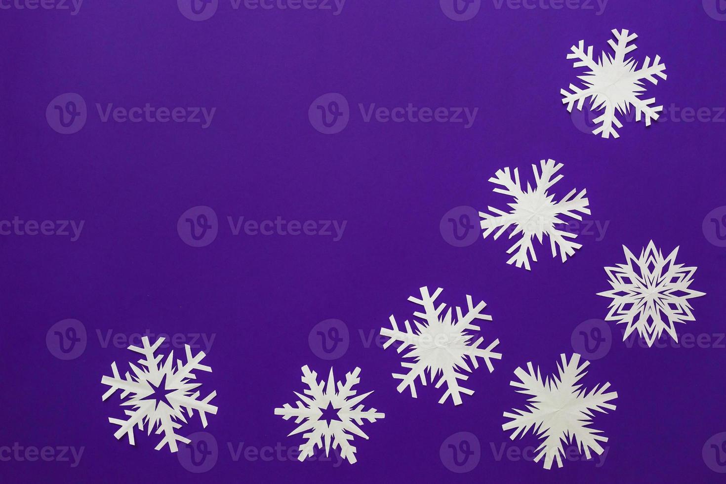 fiocchi di neve di carta bianca diverse forme e dimensioni su sfondo viola. vista dall'alto. foto