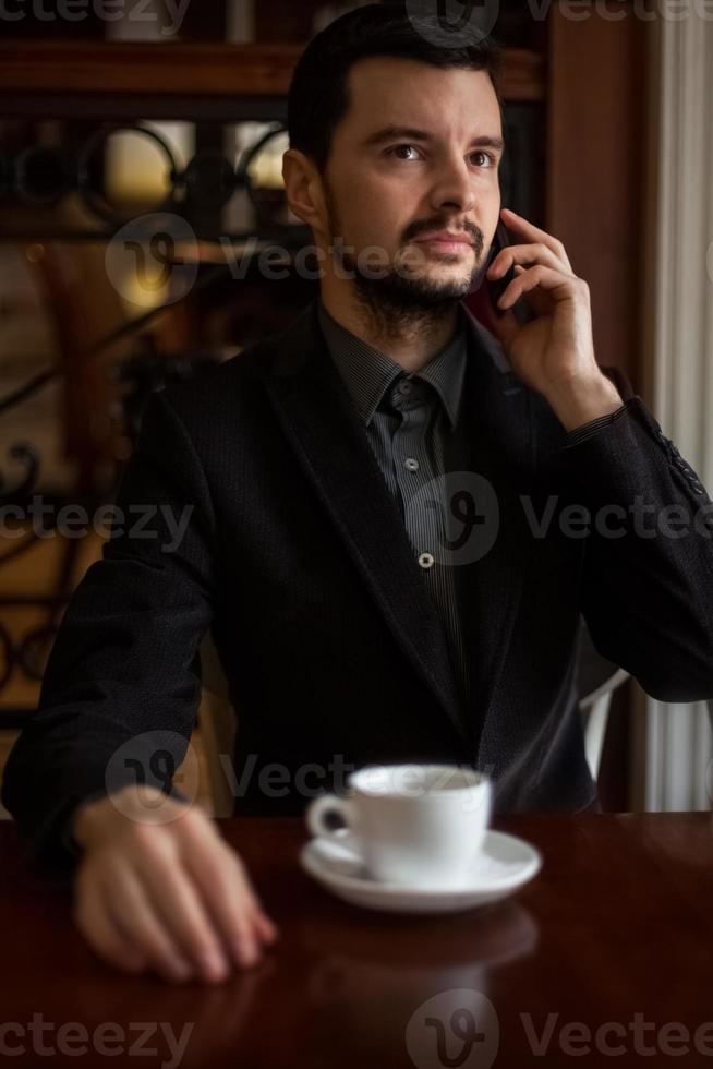 uomo d'affari bello parlare al telefono in un caffè foto