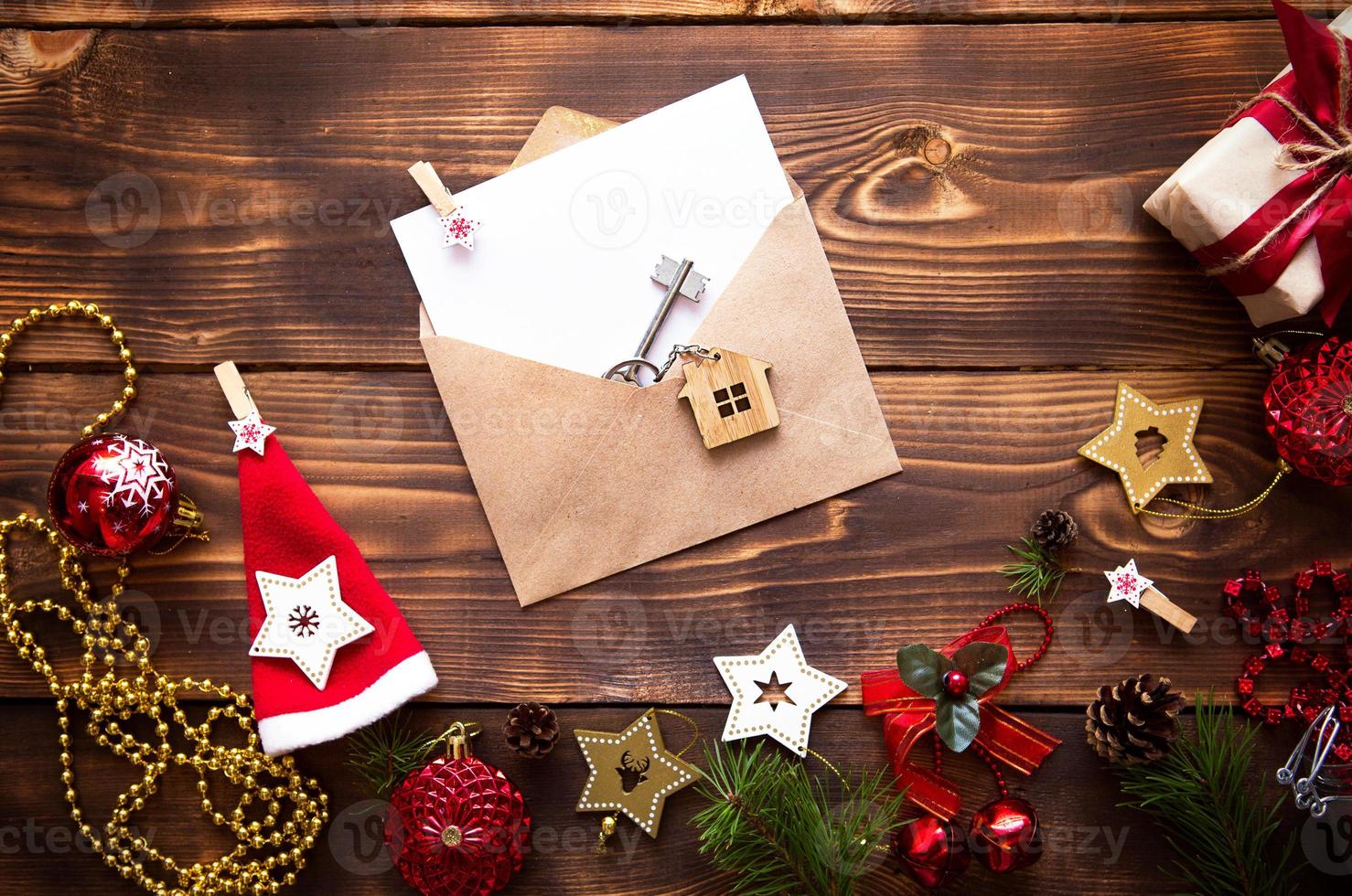 l'appartamento di natale giaceva su uno sfondo di legno con le chiavi della nuova casa al centro con una busta con un foglio di appunti. capodanno, trasferimento, quote del mutuo, affitto di un casolare. spazio per il testo foto