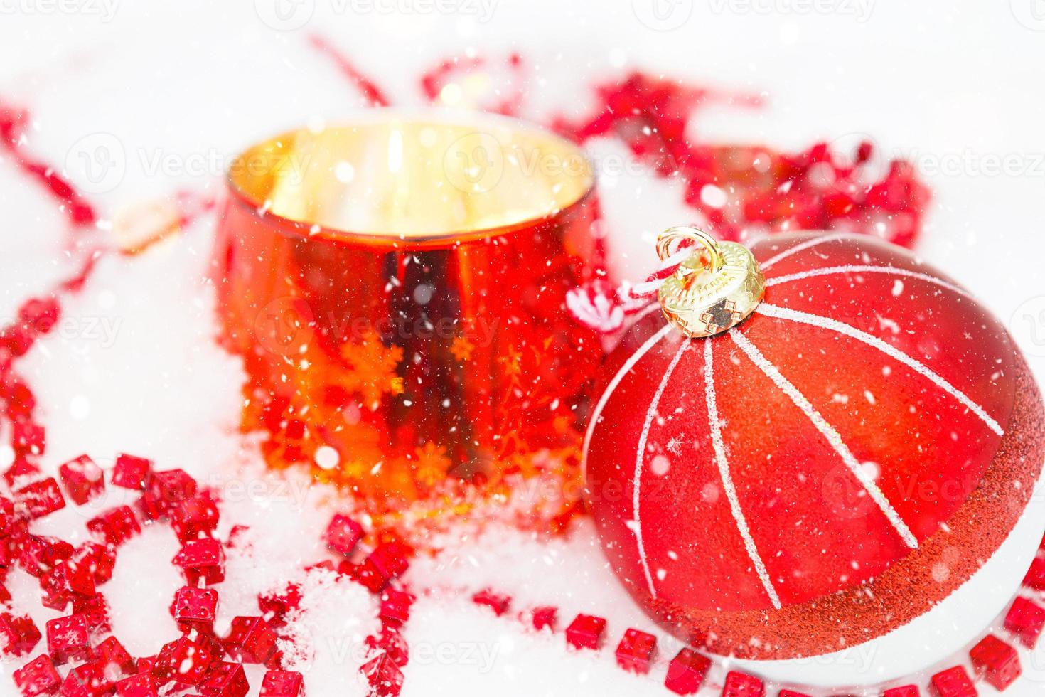 palla di natale rossa su neve bianca naturale con perline quadrate e candela accesa in un candeliere di vetro. natale, capodanno all'aperto. nevicate, atmosfera festosa di fiabe e magia, decorazione stradale. foto