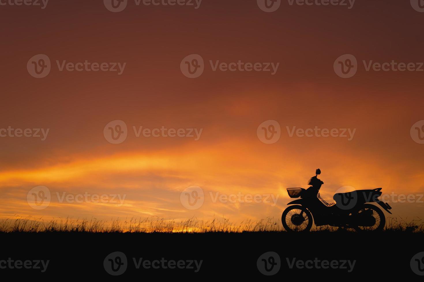cielo al tramonto arancione. silhouette motocicletta sullo sfondo del paesaggio al tramonto foto