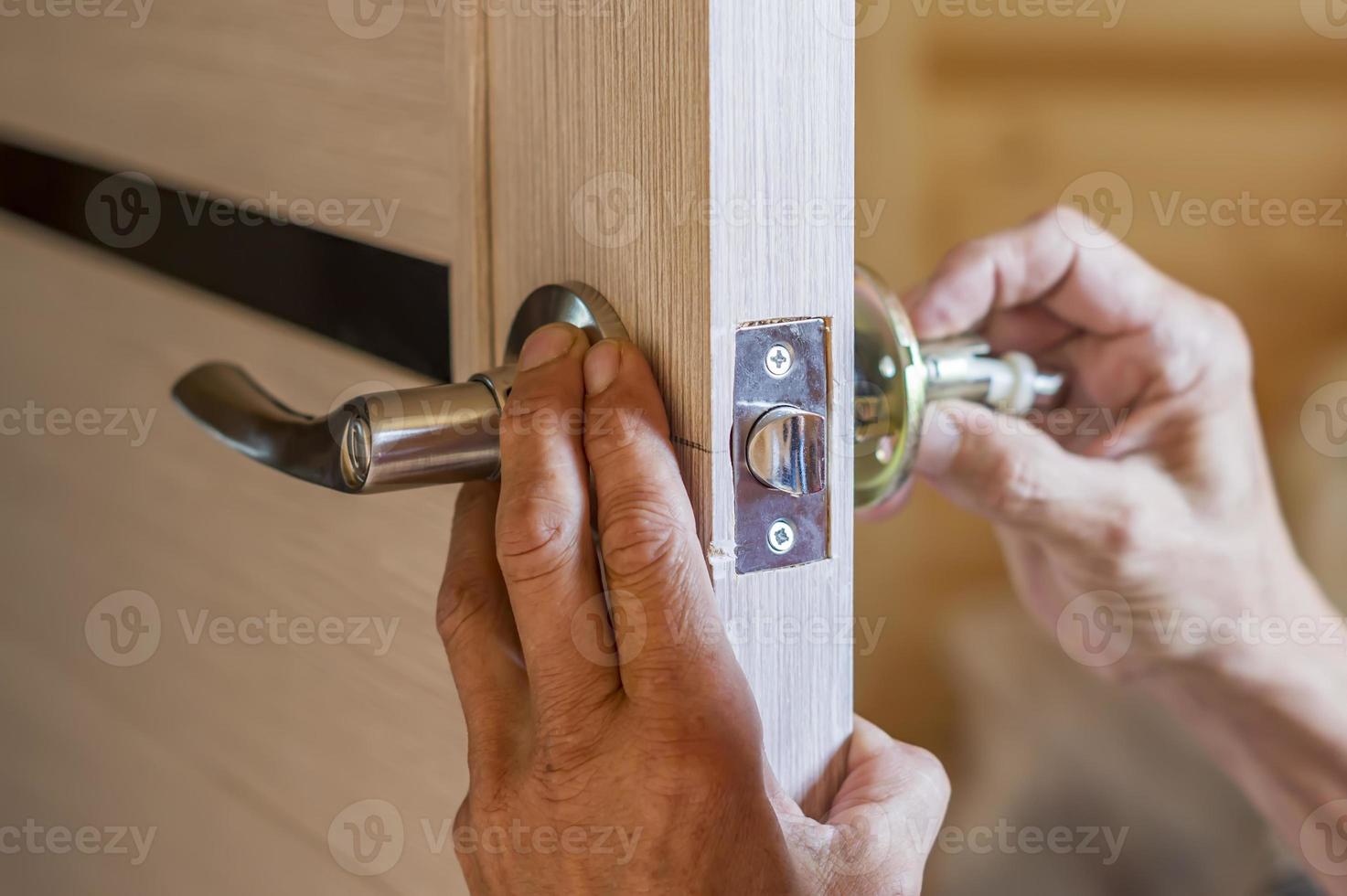 uomo che ripara la maniglia della porta. primo piano delle mani del lavoratore che installano un nuovo armadietto della porta foto