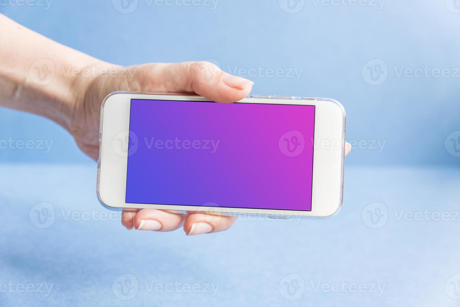 bianco moderno cellulare in mano femminile su sfondo blu foto
