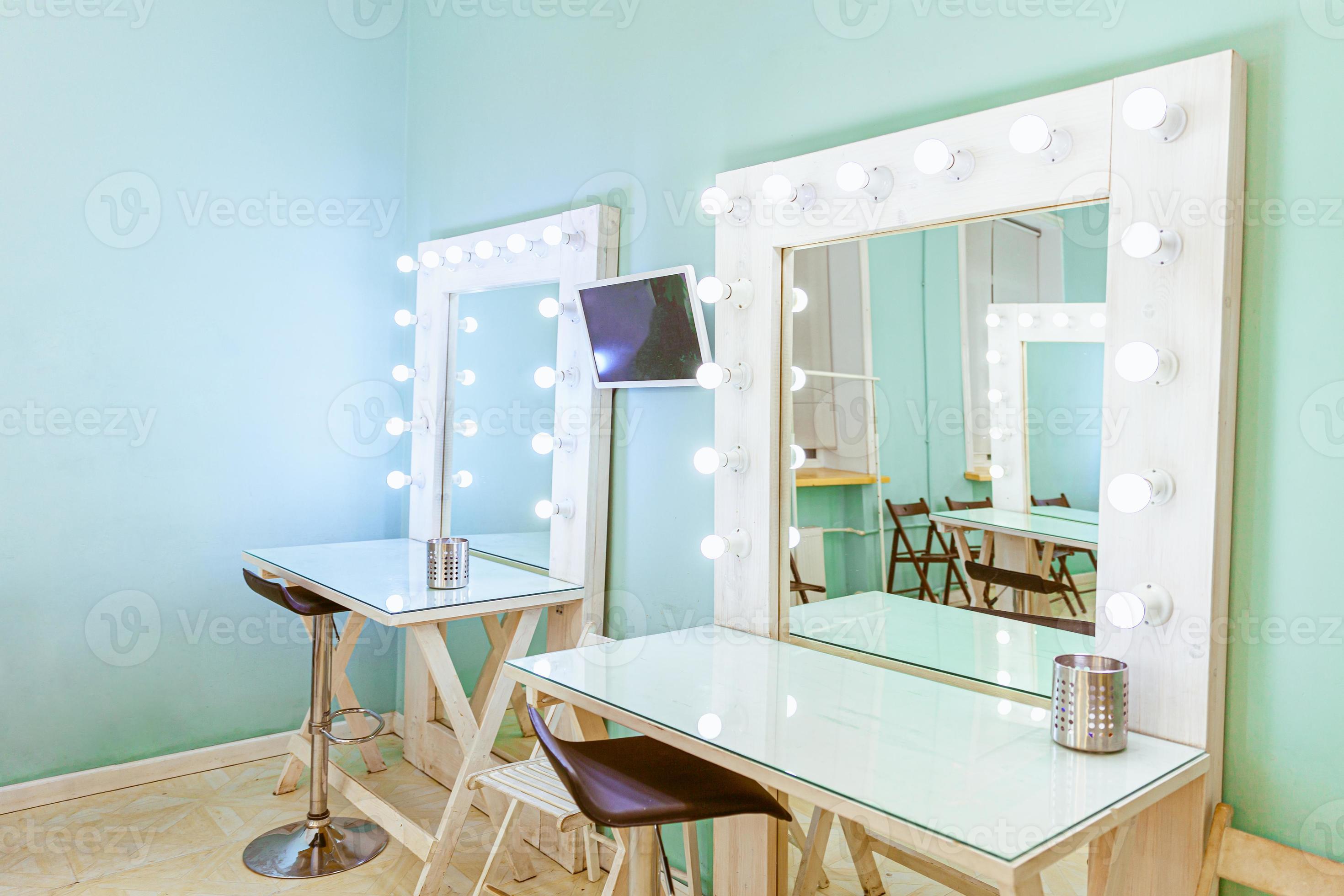 posto vuoto per il trucco della donna con specchio e lampadine. truccatore  sul posto di lavoro nella moderna sala trucco. interno del barbiere.  spogliatoio con specchio per il trucco e tavolo. design