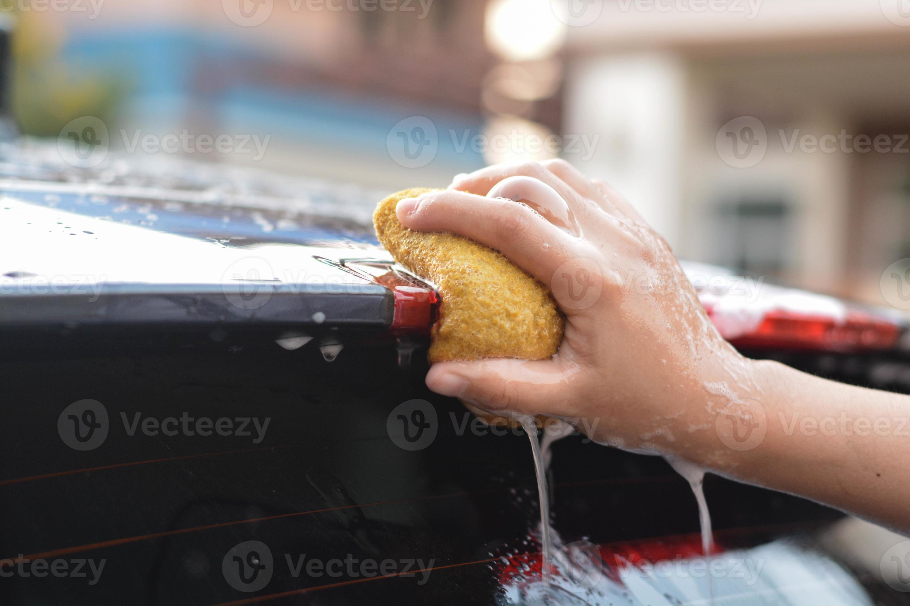 qualcuno mano catturare vecchio giallo spugna lavaggio auto spoiler il  metallico nero macchina. lavare macchina. 14165170 Stock Photo su Vecteezy