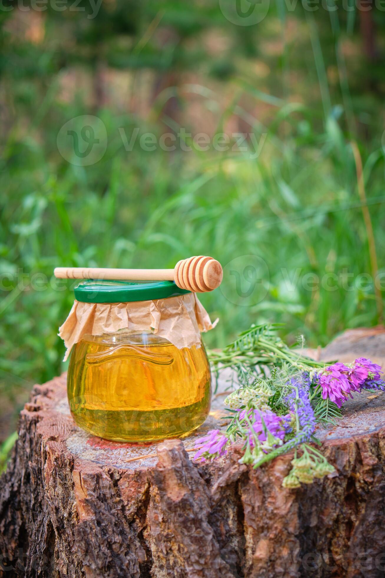 vaso miele e cucchiaio per miele nel foresta su ceppo con prato fiori.  14197117 Stock Photo su Vecteezy