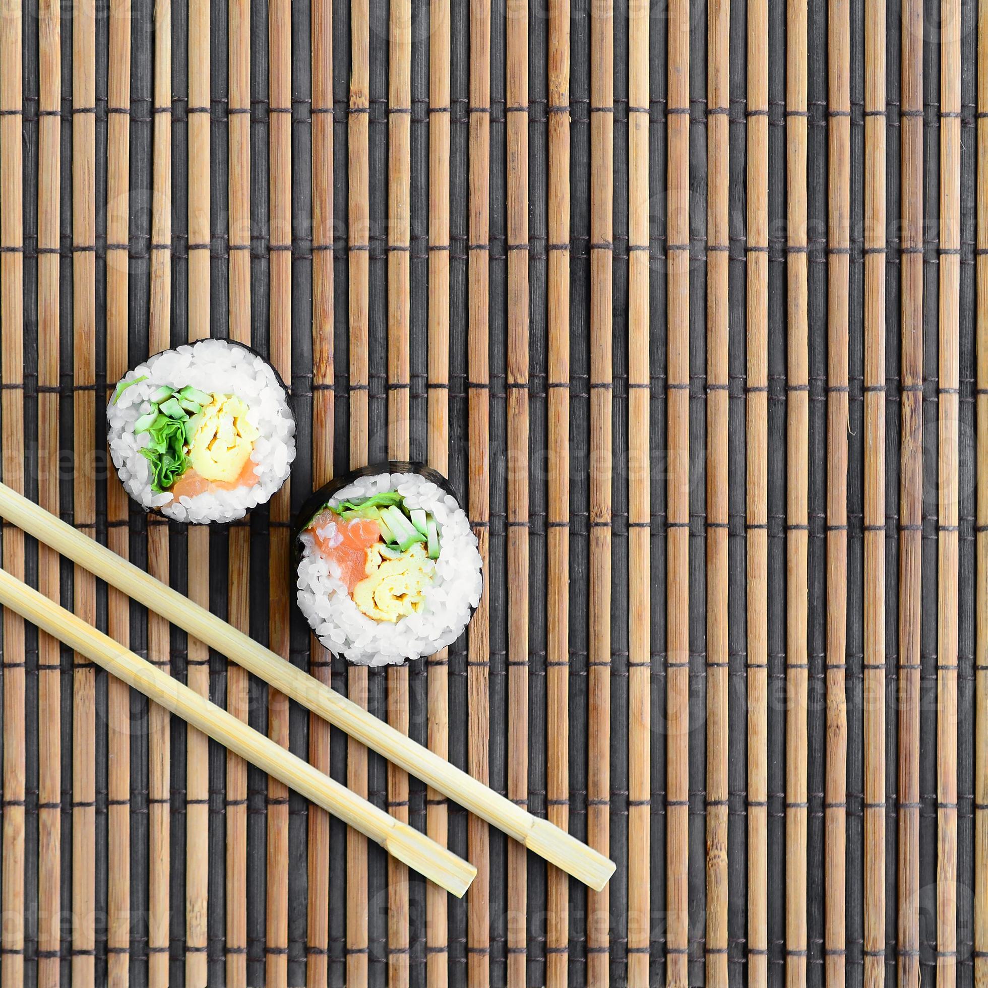 Sushi rotoli e di legno bastoncini menzogna su un' bambù cannuccia servire  stuoia. tradizionale asiatico cibo. superiore Visualizza. piatto posare  minimalismo tiro con copia spazio 14474394 Stock Photo su Vecteezy