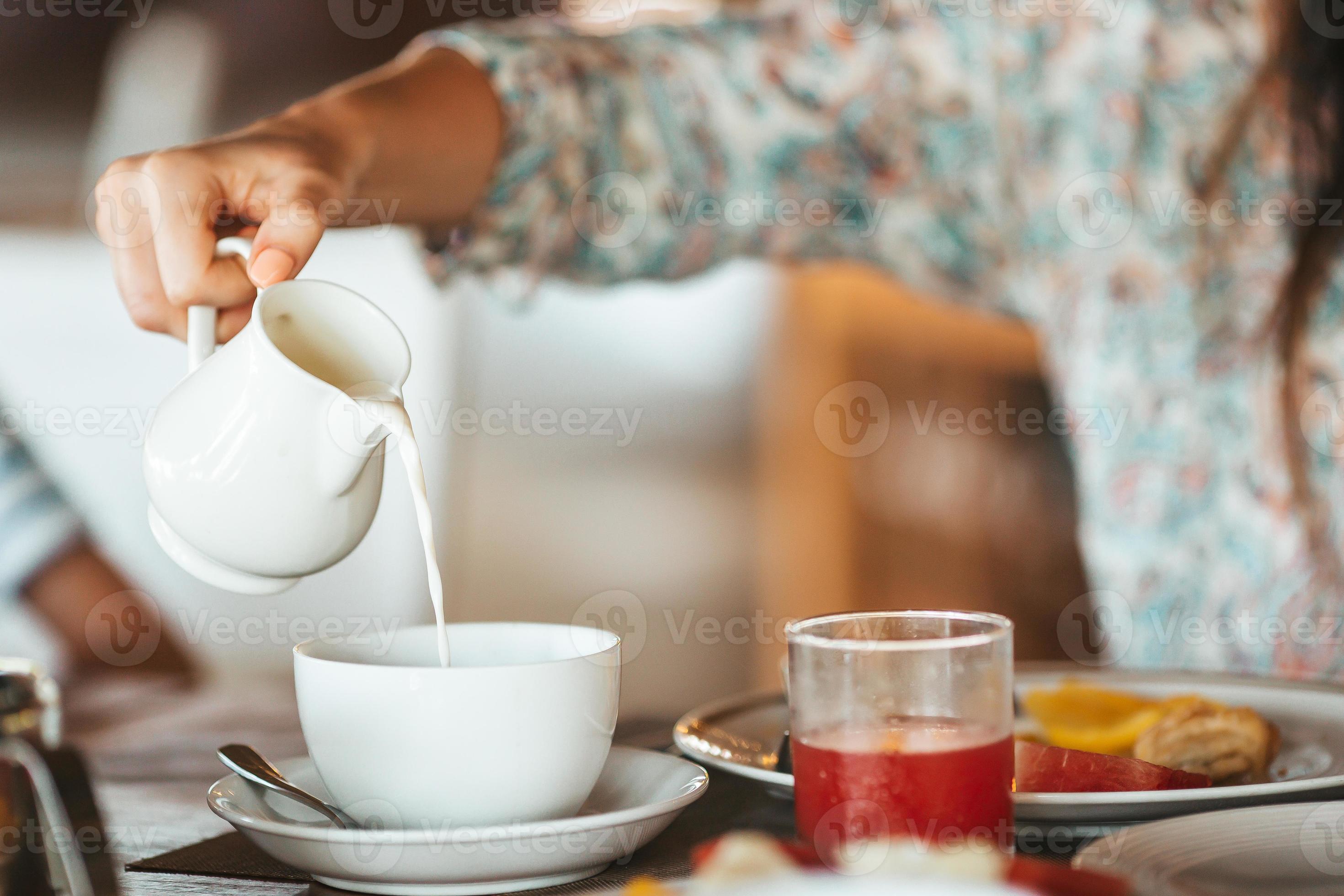 donna scrosciante latte nel boccale a partire dal bollitore